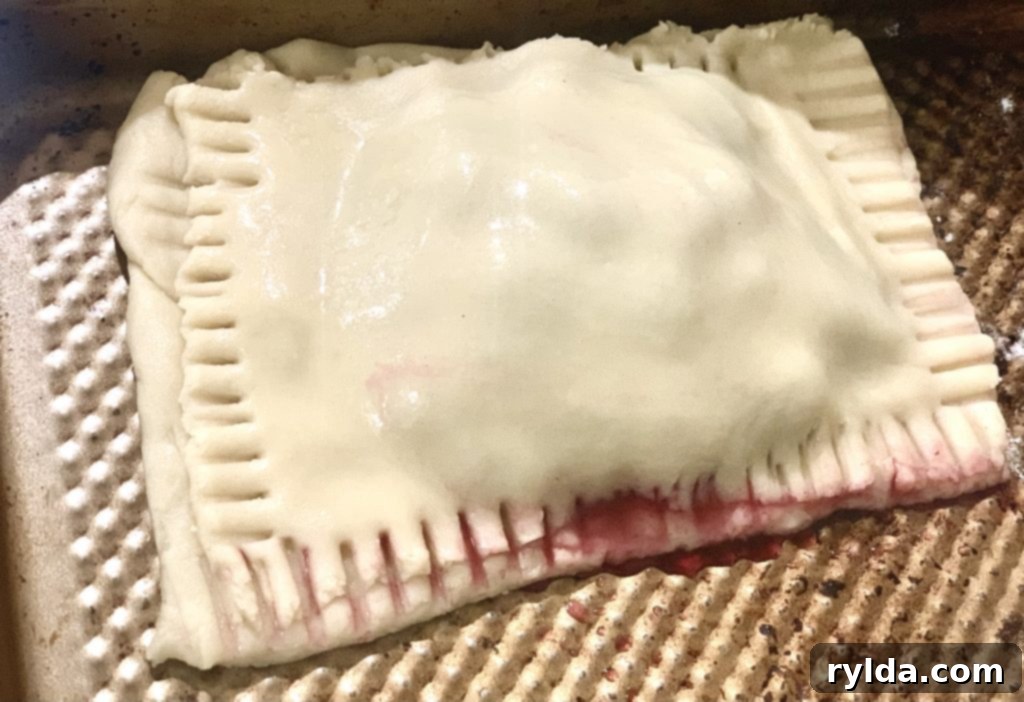 Unbaked blueberry hand pie with scored top, sealed with a fork, ready for the oven.