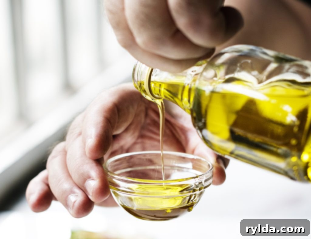 Hands pouring extra virgin olive oil over fresh asparagus