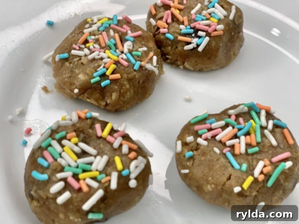 Unbaked sprinkle-coated cookie dough balls on a baking sheet, ready for the oven