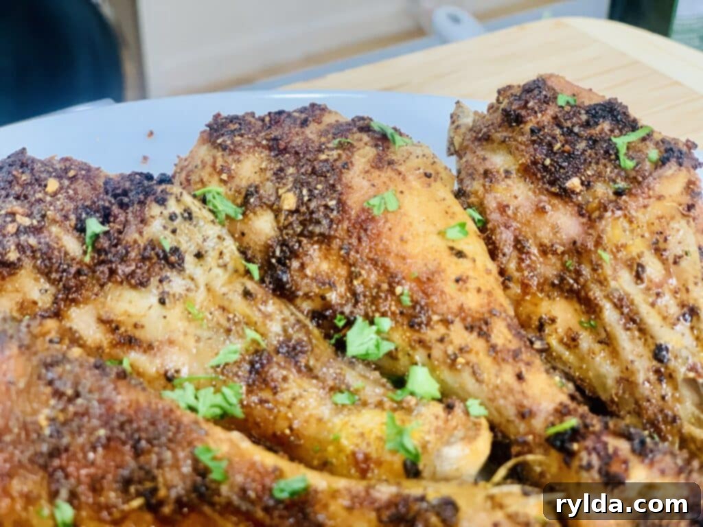 Two hands holding a perfectly baked chicken drumstick with a bite taken out