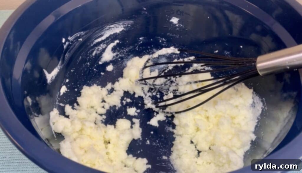 Granulated sugar and softened butter in a mixing bowl, being creamed together with an electric mixer.