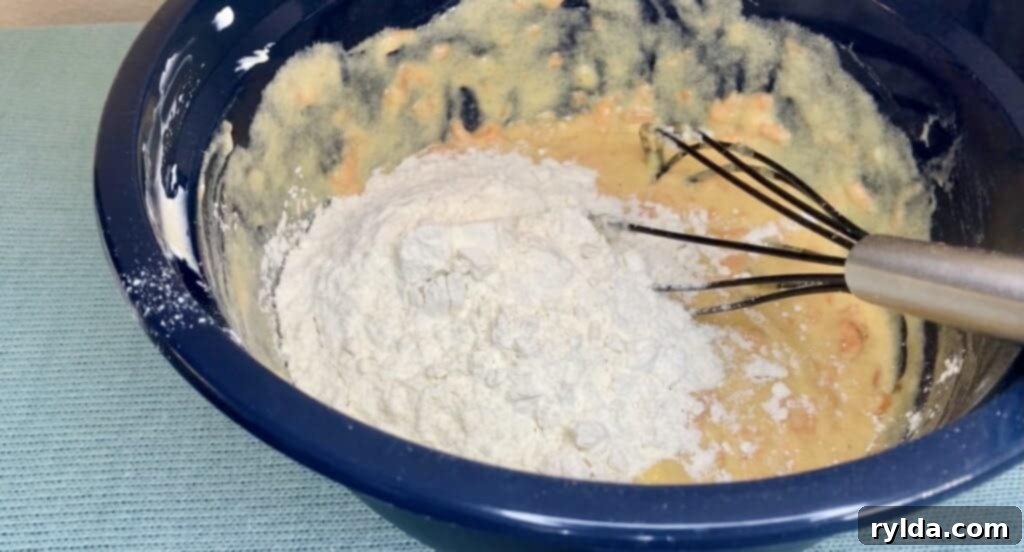 Adding dry ingredients (flour, baking powder, salt) into the wet mixture, gently folded to combine.