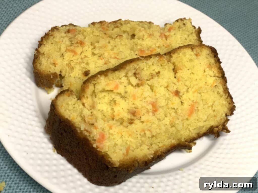 A perfectly baked, golden-brown Banana Carrot Loaf, sliced to reveal its moist interior with flecks of banana and carrot.