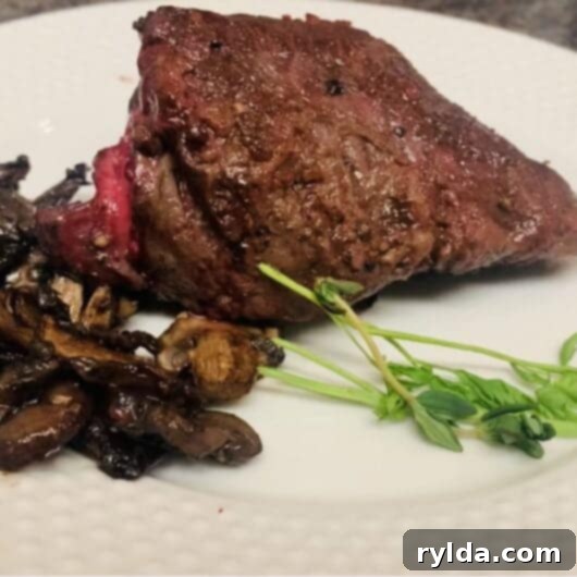 Tender Pan-Seared Filet Mignon with Savory Mushrooms 3 A perfectly cooked pan-seared filet mignon steak topped with sautéed mushrooms, glistening with a rich sauce.