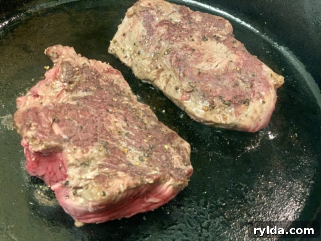 Tender Pan-Seared Filet Mignon with Savory Mushrooms 4 Two filet mignon steaks perfectly seared in a cast iron skillet, golden brown and ready for the oven.