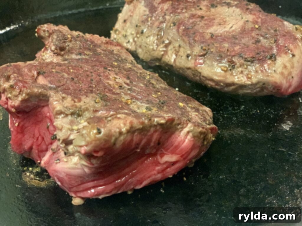 Tender Pan-Seared Filet Mignon with Savory Mushrooms 5 Another view of the expertly seared filet mignon steaks in a sturdy cast iron skillet.