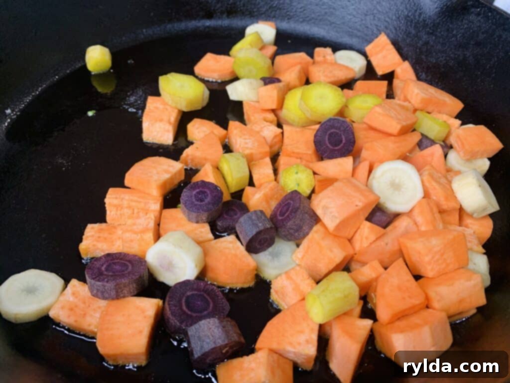 Close-up of roasted carrots and sweet potatoes in a skillet.