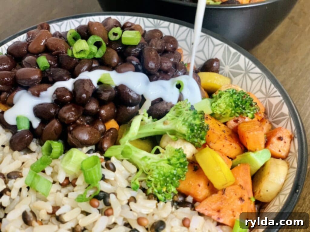 A close-up of a grain bowl with cooked rice, vegetables, and black beans.