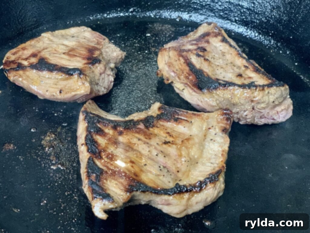 Pan-seared flank steak cooking in a skillet