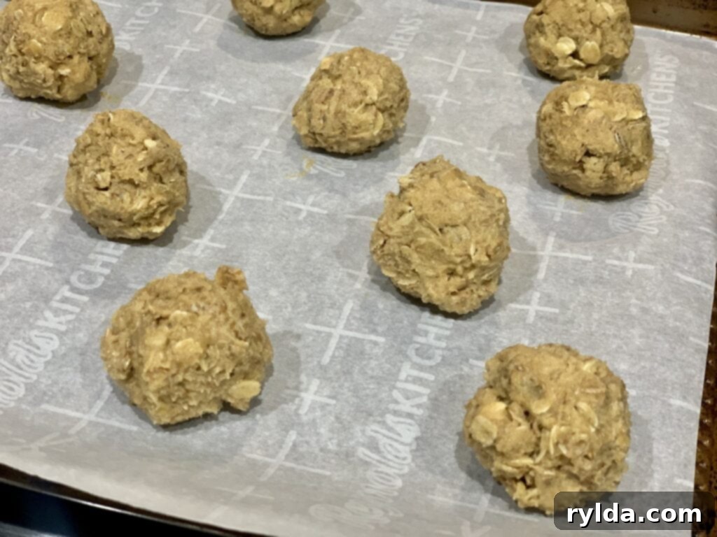 Freshly baked peanut butter oatmeal cookies cooling on a baking sheet, with golden edges.