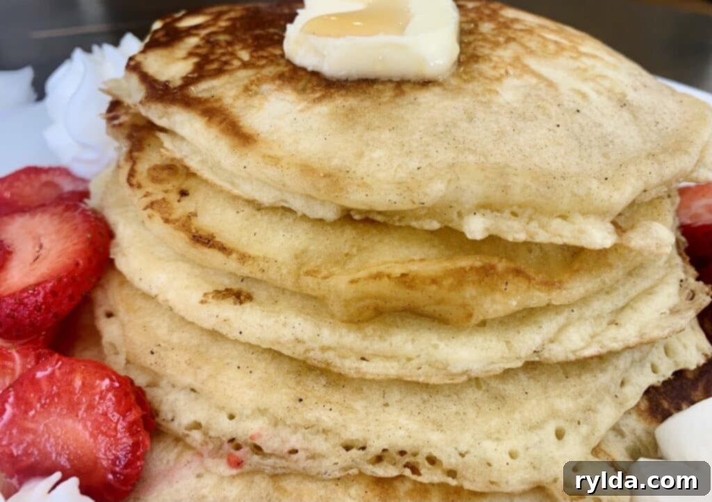 A beautifully plated stack of fluffy buttermilk pancakes with a melting pat of butter