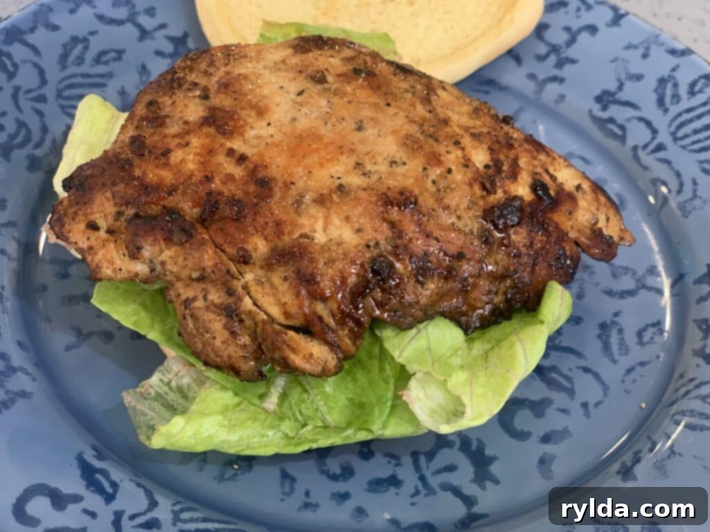 Assembled homemade chicken sandwich with fresh lettuce and a soft brioche bun, ready to be served.