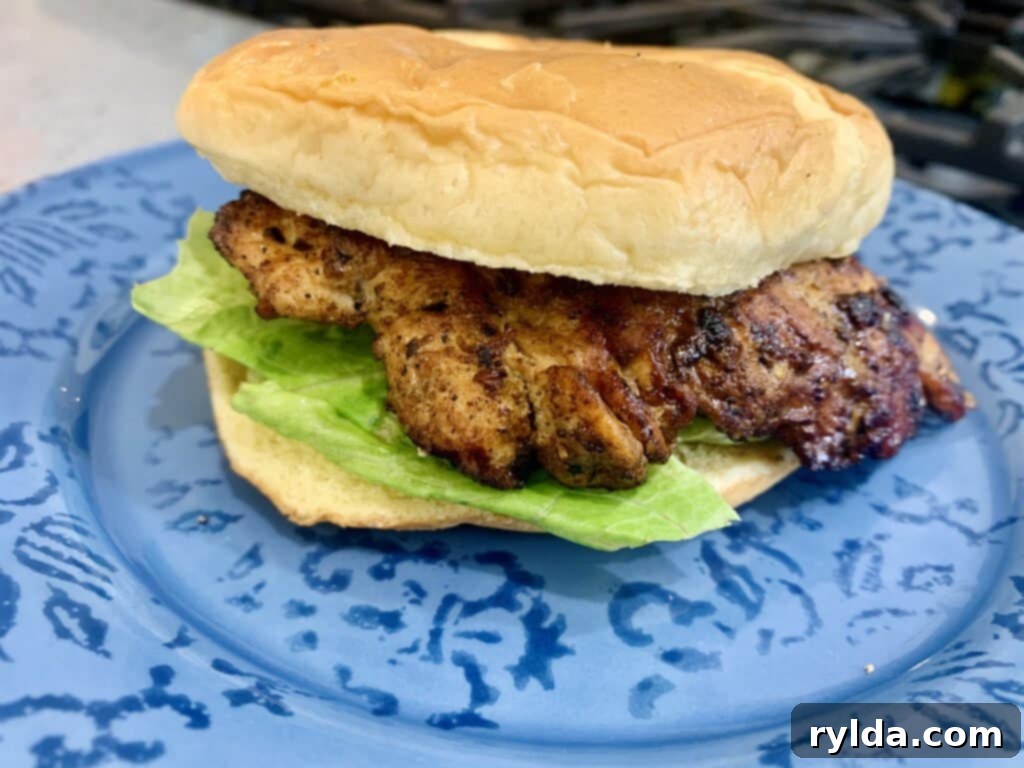 Top-down view of a delicious homemade chicken sandwich with a golden-brown chicken breast and fresh toppings.