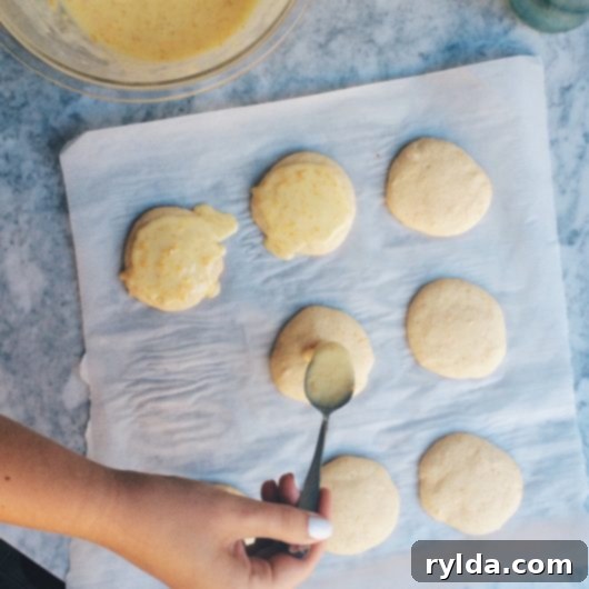 Delicious baked Frozen Lemonade Cookies on a cooling rack with a glass of lemonade nearby, ready to be glazed.